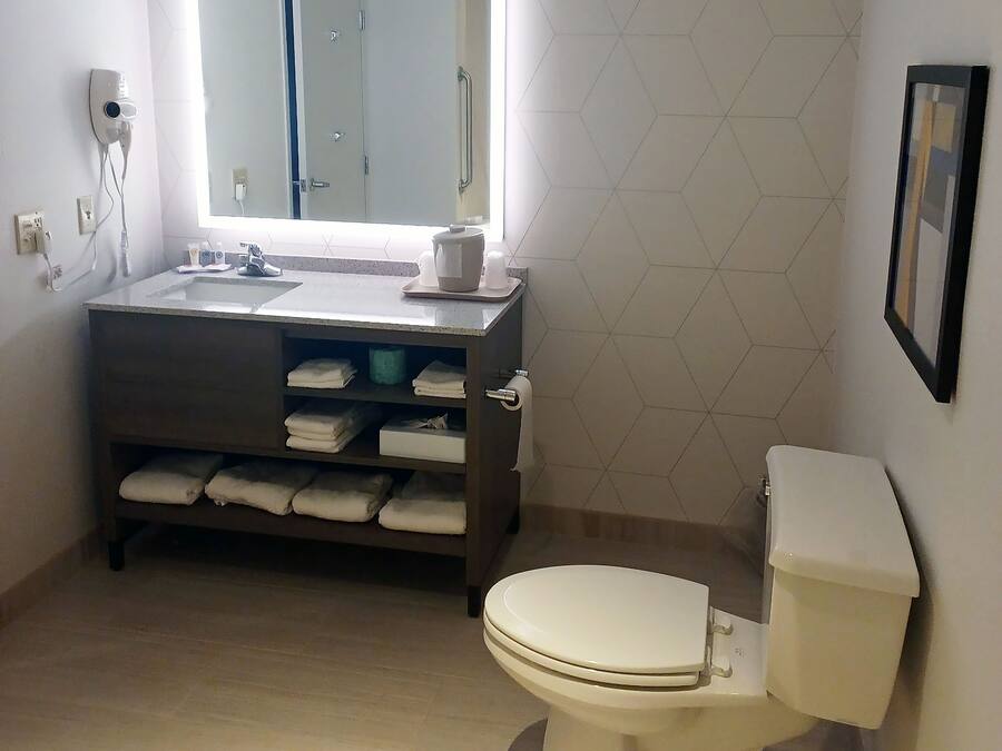 A bathroom with a toilet, sink, and mirror.