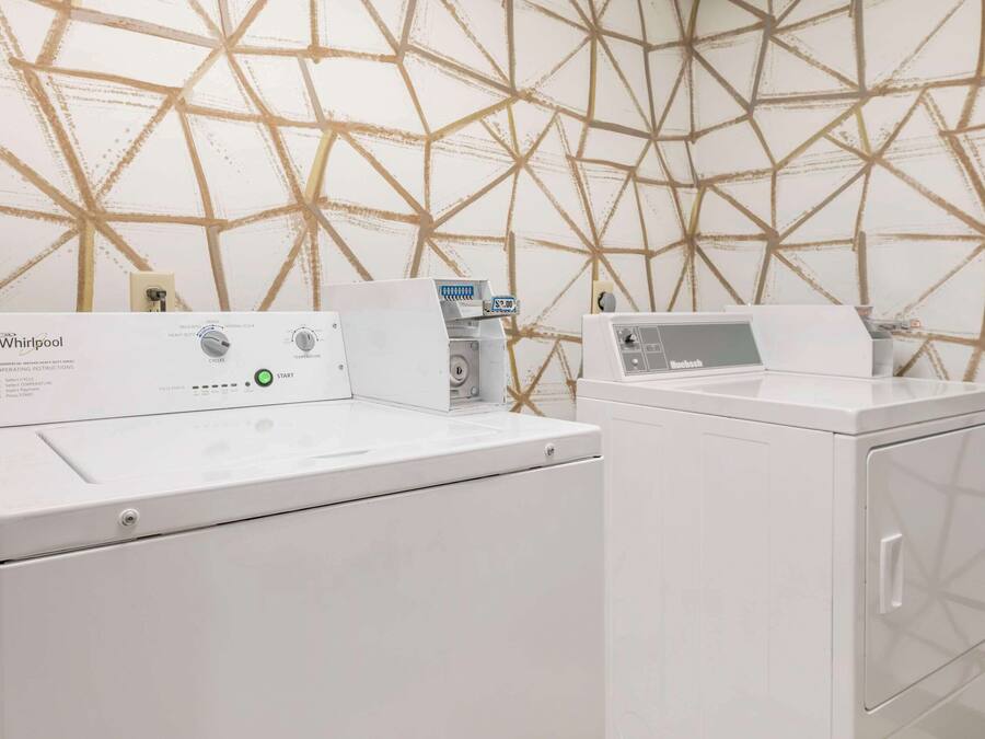 A Whirlpool washer and dryer in a laundry room with a geometric patterned wall.