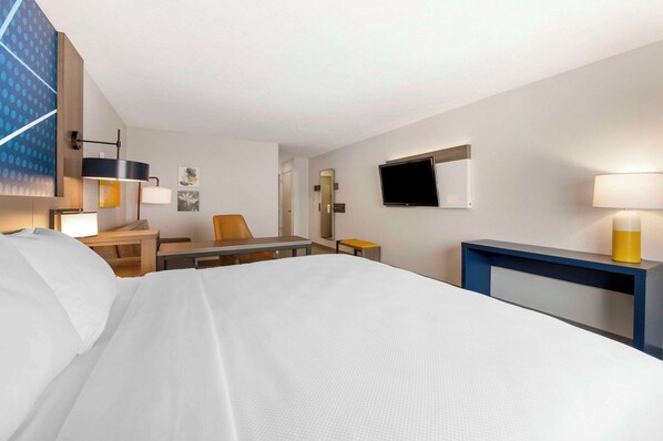 A hotel room with a large bed, a desk with a chair, a television, and a small table with a lamp. - Comfort Inn Edinburgh - Columbus (Edinburgh)