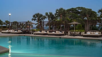 Una piscina al aire libre, sombrillas, sillones reclinables de piscina