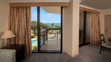 Quarto de hotel com vista para uma piscina e vegetação.