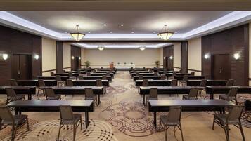 A conference room with multiple tables and chairs, a patterned carpet, and ceiling lights.