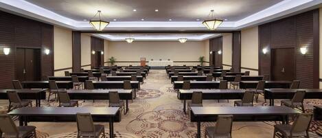A conference room with multiple tables and chairs, a patterned carpet, and ceiling lights.