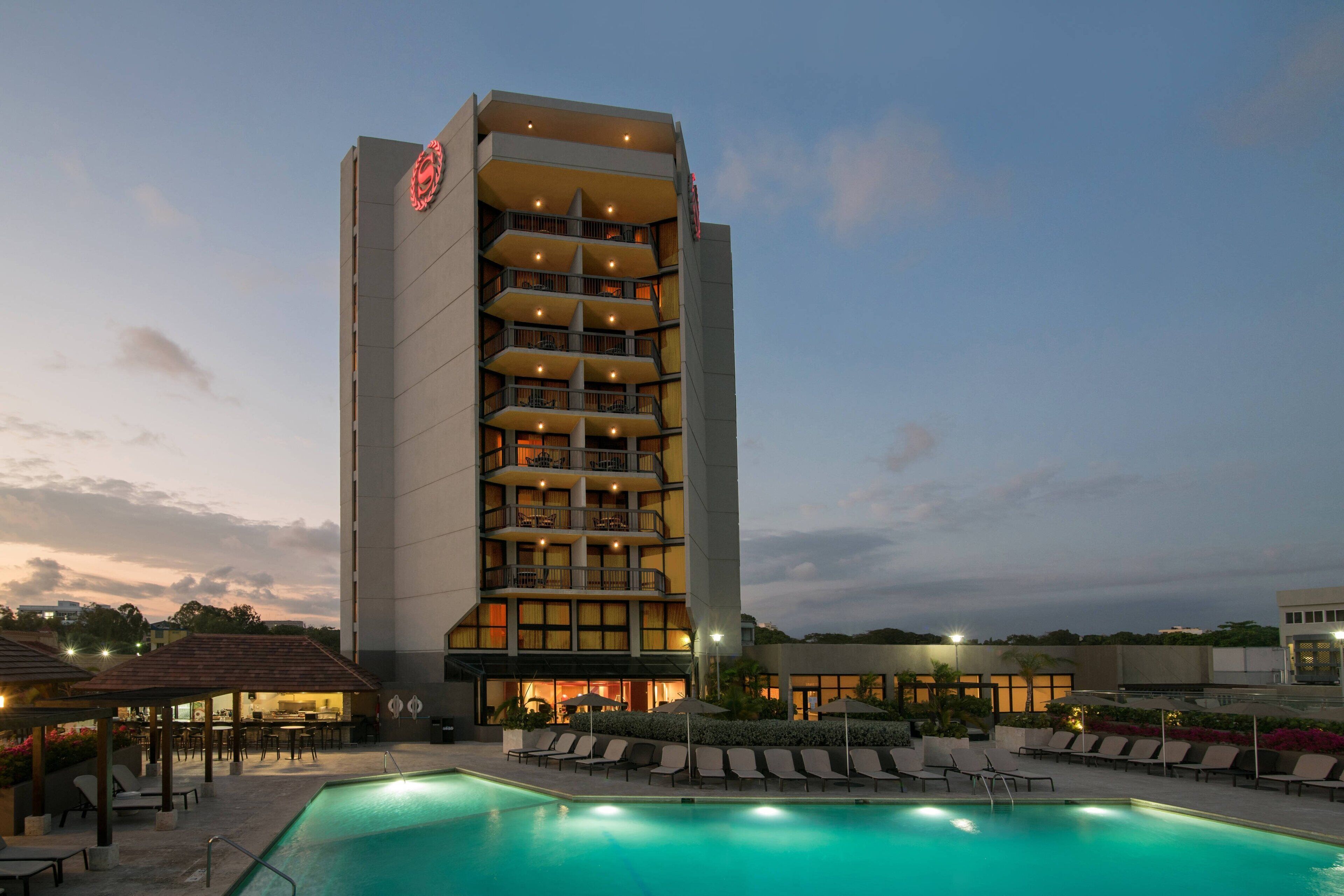 A hotel with a pool, outdoor seating, and a large building with multiple balconies.