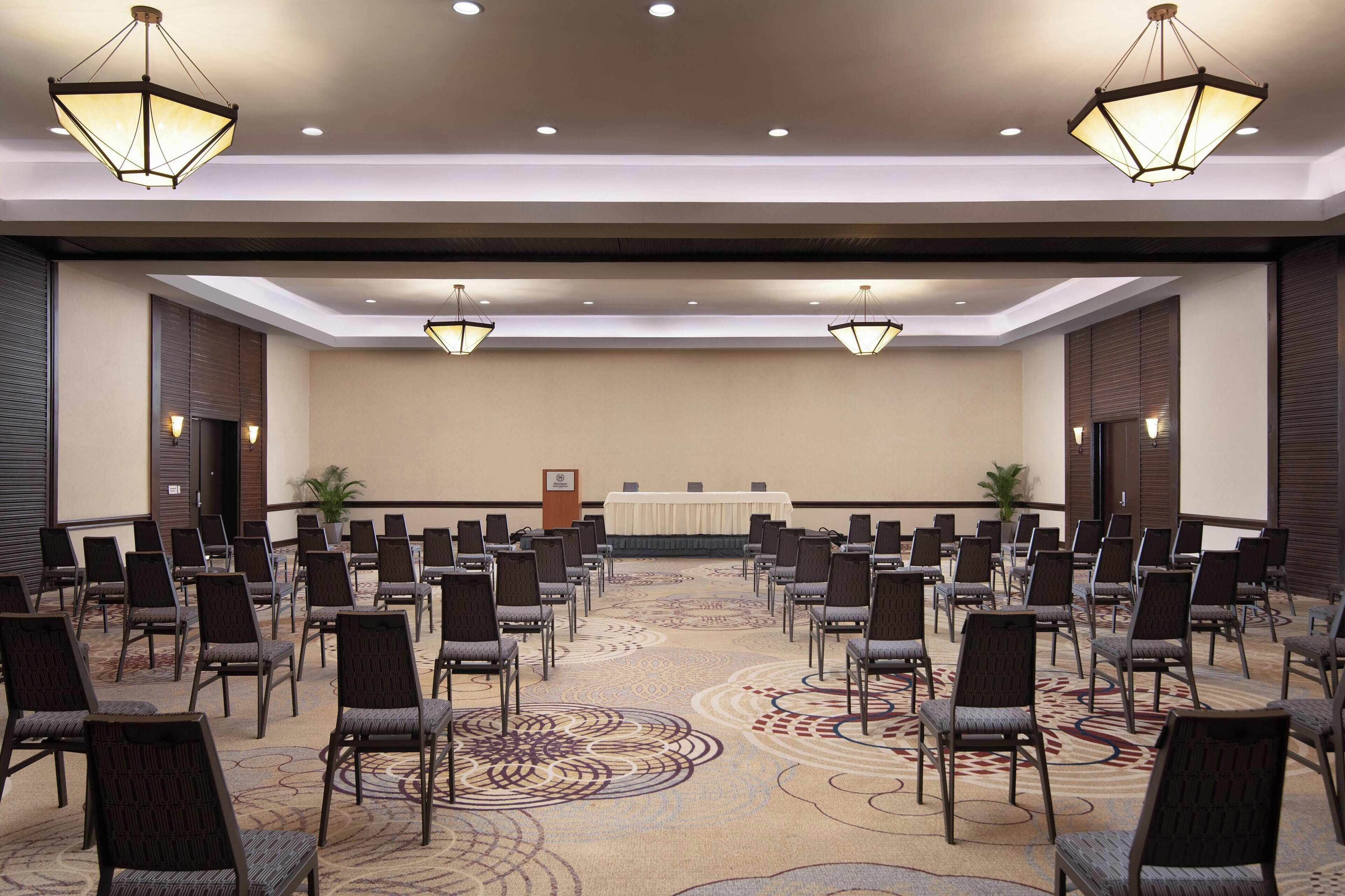A conference room with rows of chairs, a podium, and a carpeted floor.