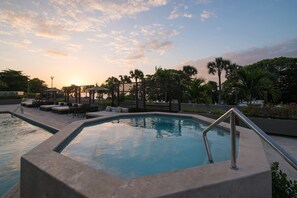Una piscina con una zona de estar hundida y una estructura de pérgola.