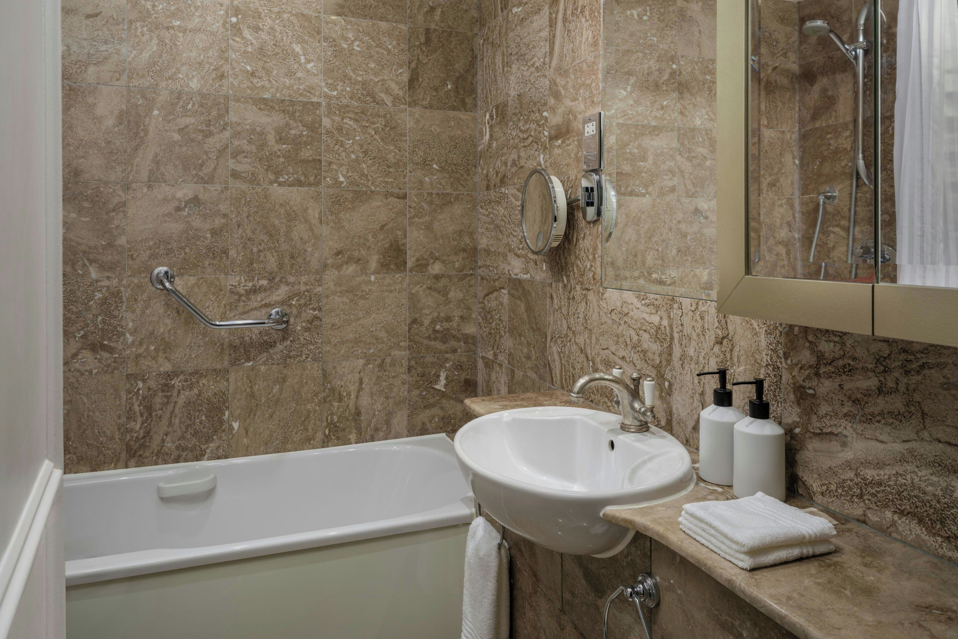 A bathroom with a bathtub, sink, and mirror.