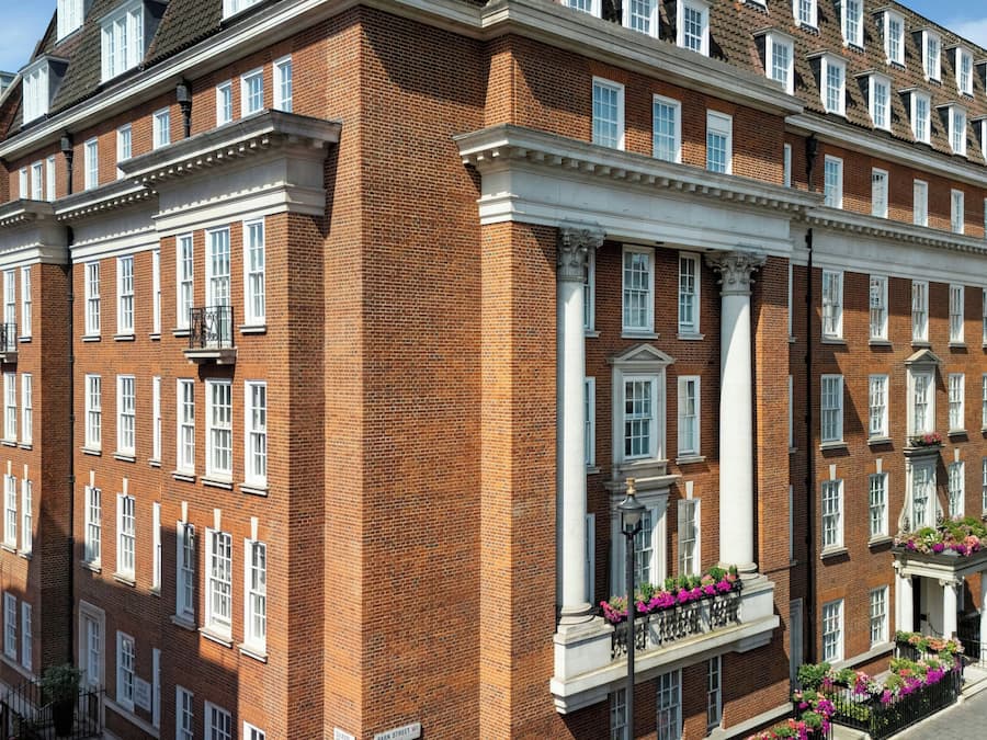Un edificio de ladrillo de varios pisos con marcos de ventana blancos, una entrada central con una columna decorativa y un letrero que indica 'Park Street W1'.