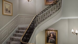 Una imponente escalera con barandillas negras ornamentadas y paneles de pared blancos.