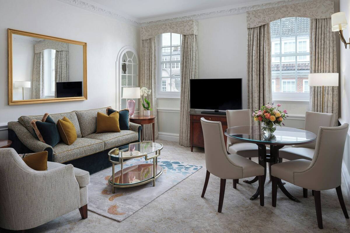 Een woonkamer met een bank, fauteuils, een salontafel, een televisie en een eettafel met stoelen.