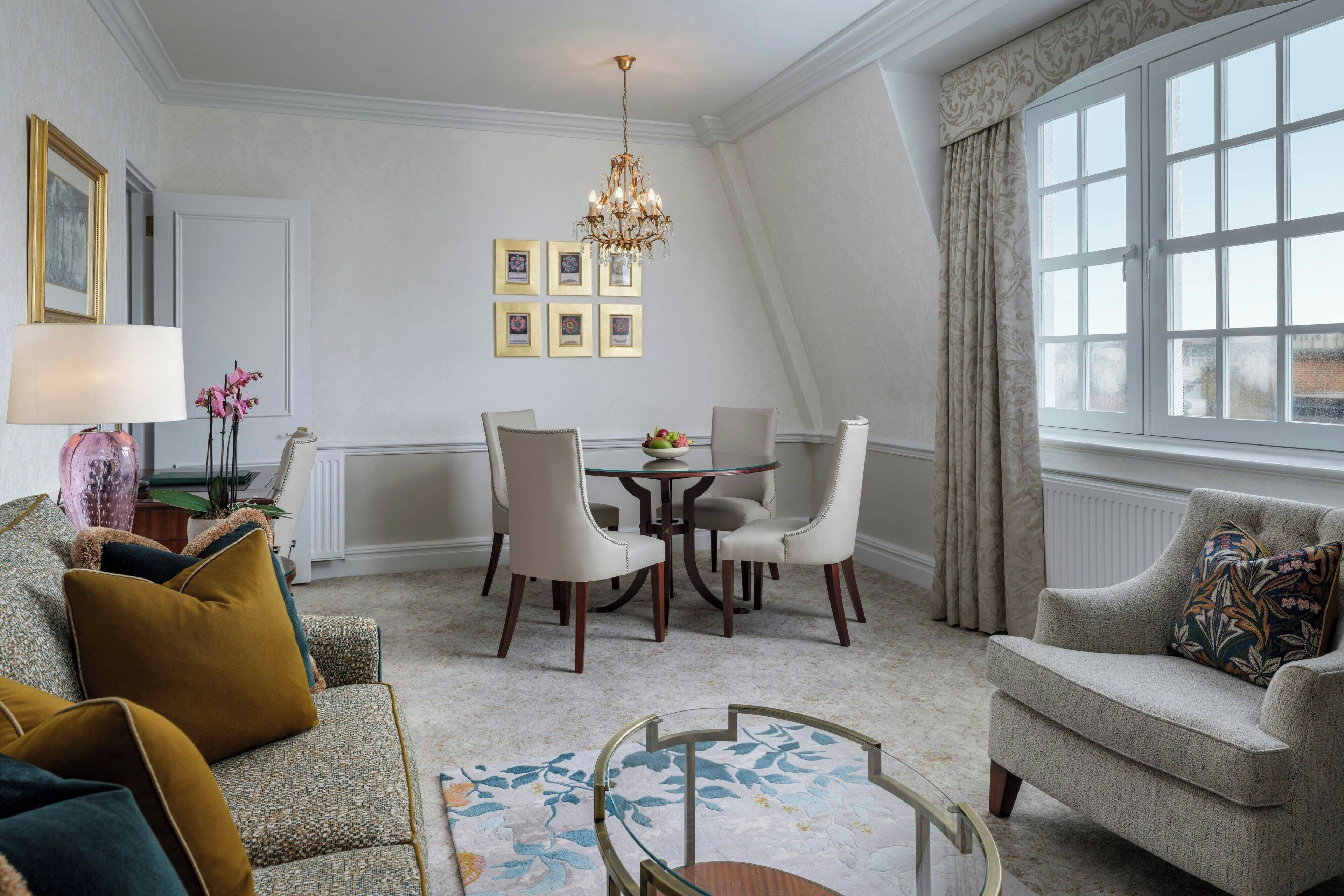 A dining area with a round table, chairs, a chandelier, and a sofa.