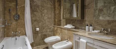 A bathroom with a bathtub, a shower, a bidet, a sink, and a mirror.
