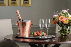A copper champagne bucket with a bottle, two empty glasses, and a plate with strawberries on a round table. - 47 Park Street - Grand Residences by Marriott (London)