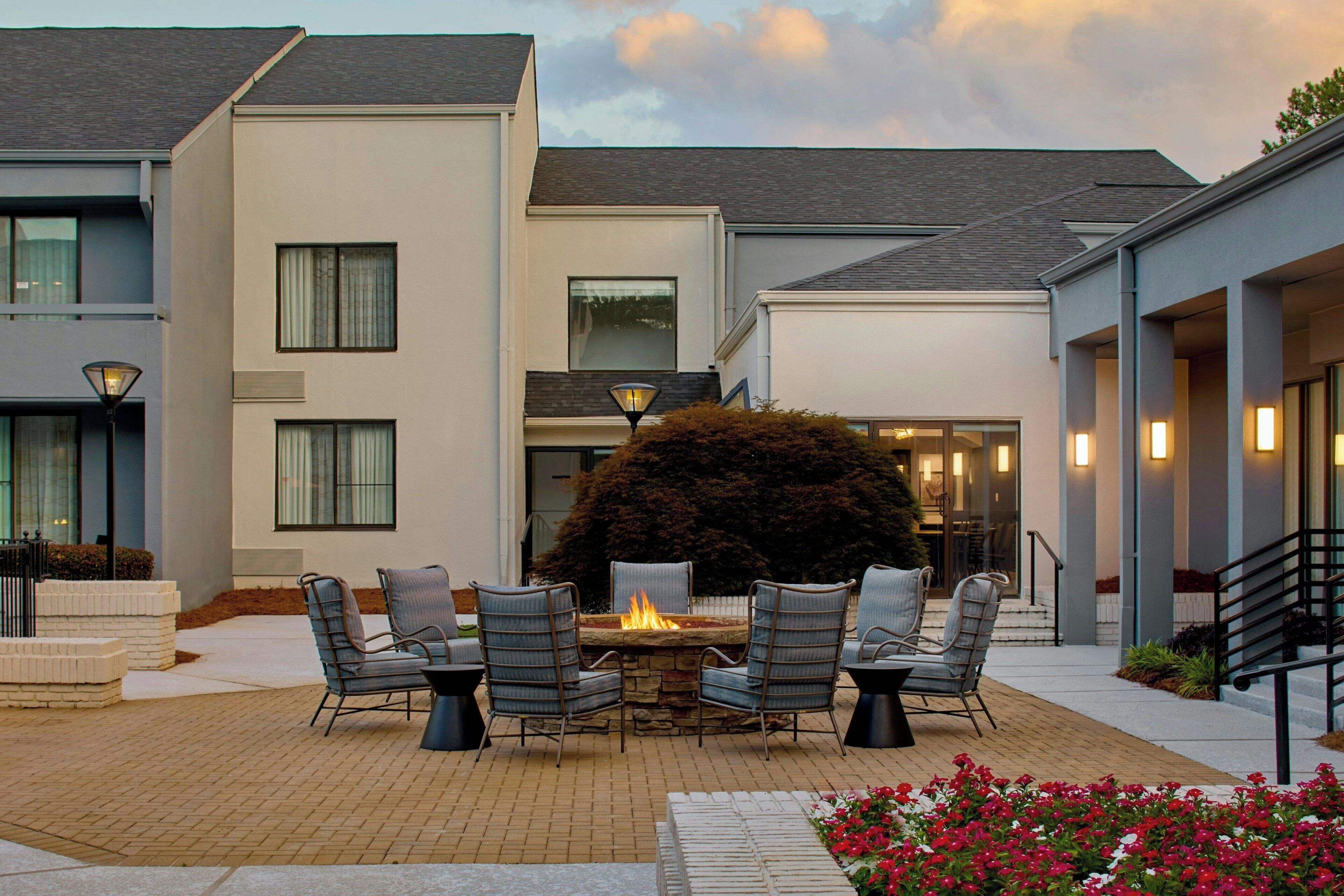 A patio with a fire pit, outdoor seating, and a view of the building's exterior.