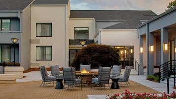 A patio with a fire pit, outdoor seating, and a view of the building's exterior.
