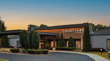 Un hotel Courtyard by Marriott con diseño moderno, que presenta una entrada cubierta y jardines bien cuidados.