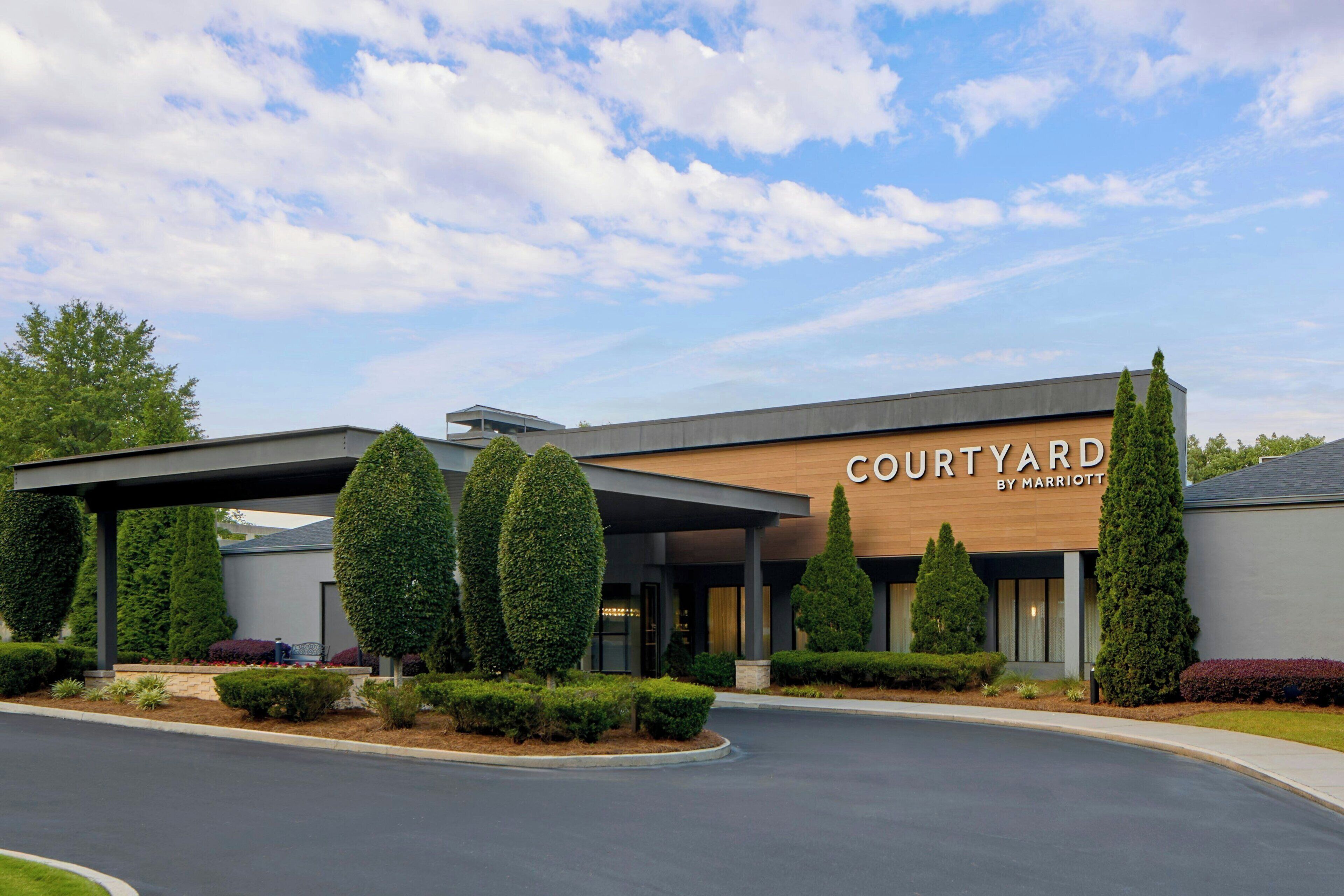A Courtyard by Marriott hotel with a modern design, featuring a covered entrance and well-maintained landscaping.