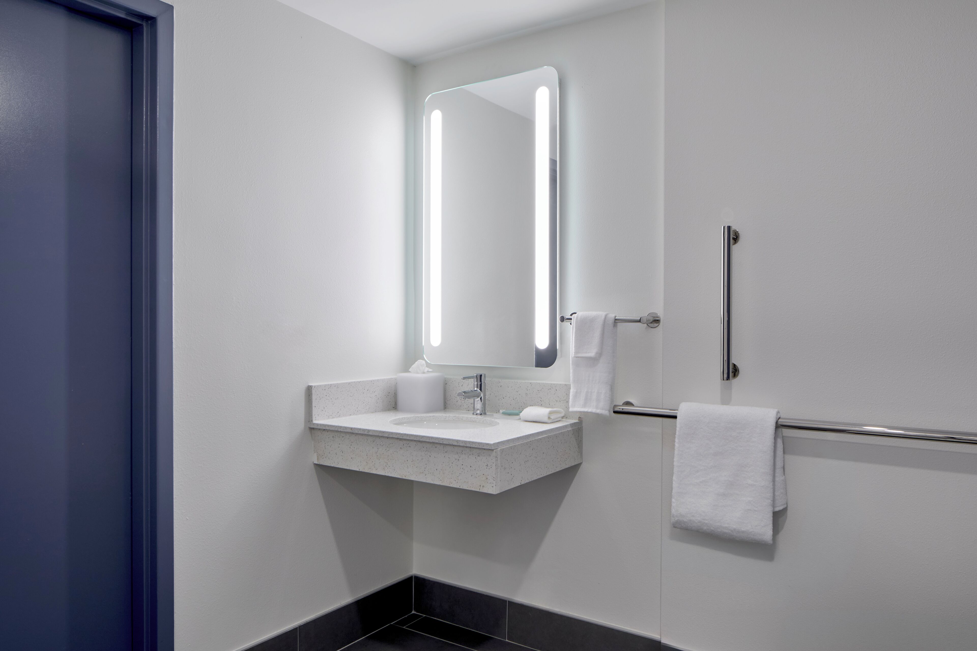 A modern bathroom with a white sink, a mirror, and a towel rack.