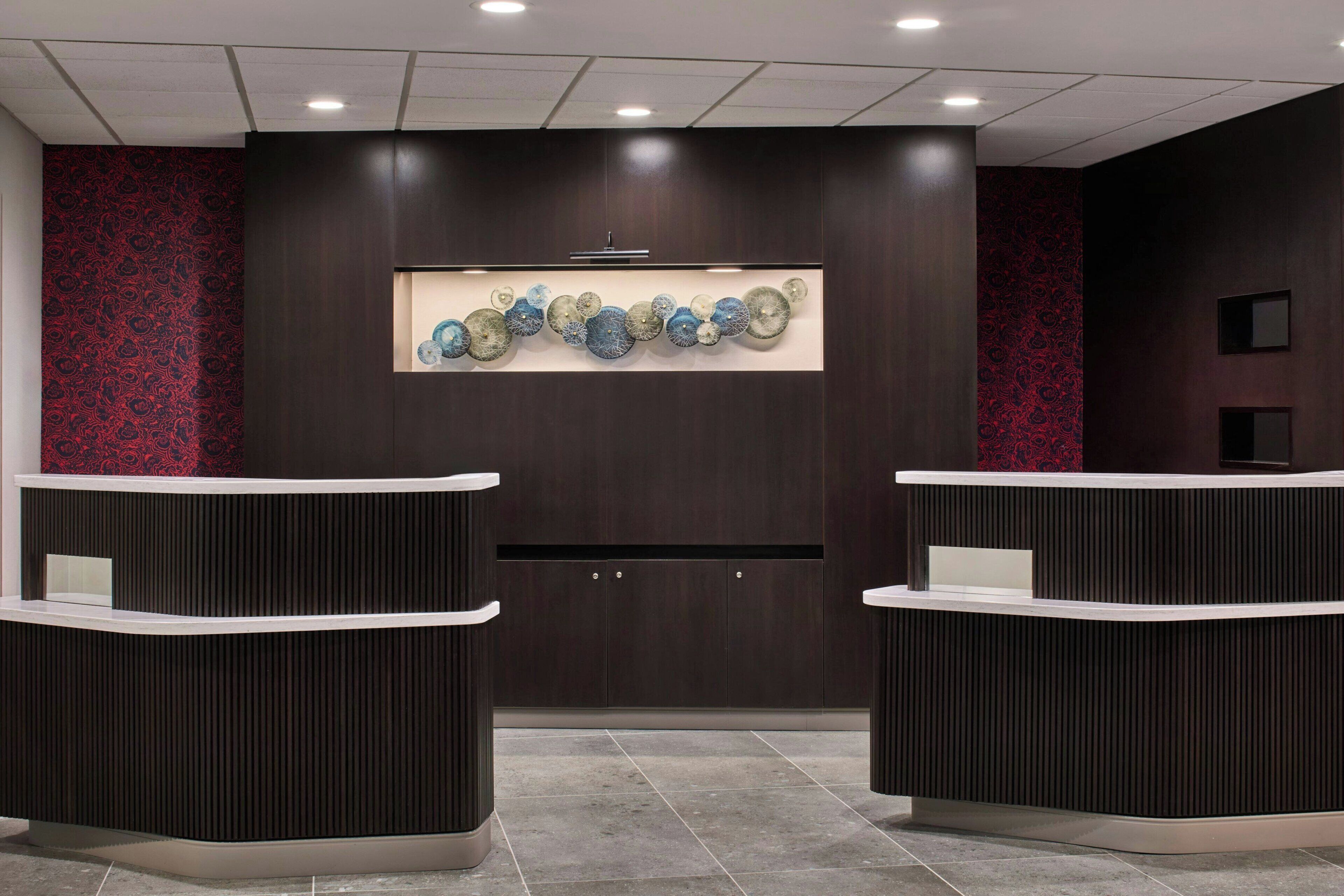 Ett välkomstområde med två böjda receptionsdiskar, en väggmonterad utställning av dekorativa glasobjekt och en vägg med ett mönster på vardera sidan.