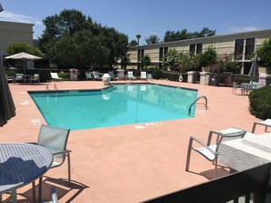 Relax by the pool surrounded by comfortable lounge chairs and shaded tables.