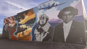 A mural with multiple figures and a plane. - Holiday Inn Lumberton by IHG (Lumberton)