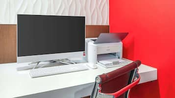 A modern office desk with a desktop computer, a printer, and a keyboard.