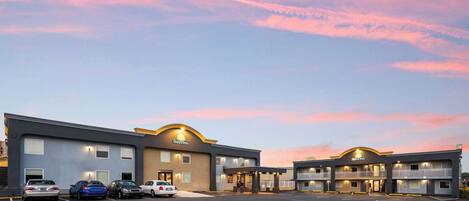 A Days Inn with a parking lot, multiple floors, and a sunset sky.