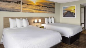 Habitació d'hotel amb dos llits, ambres de fusta, roba de llit blanca i dues làmpades penjades a la paret.