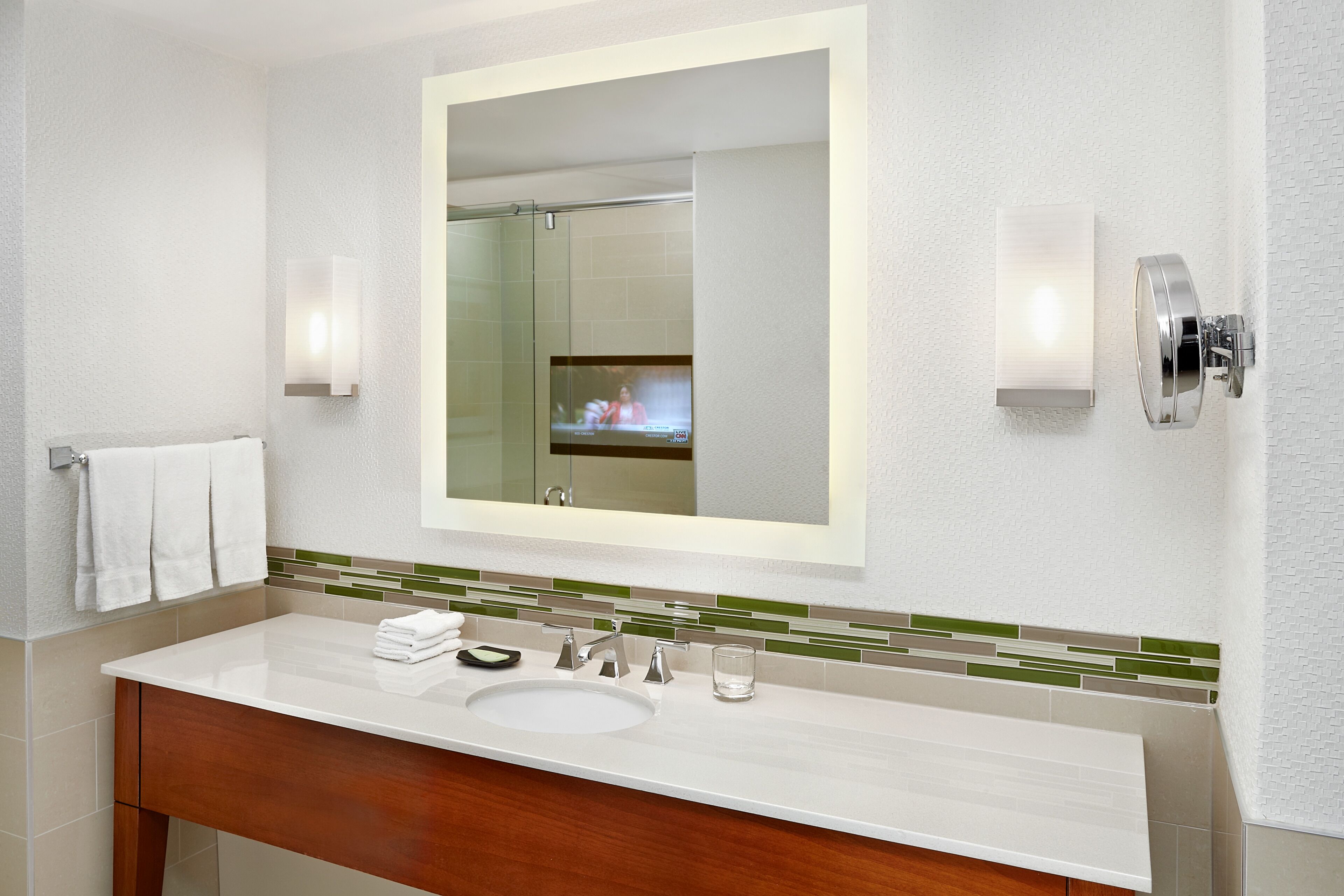 Un baño moderno con un espejo grande, un lavabo y dos luces empotradas.