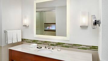 Un baño moderno con un espejo grande, un lavabo y dos luces empotradas.