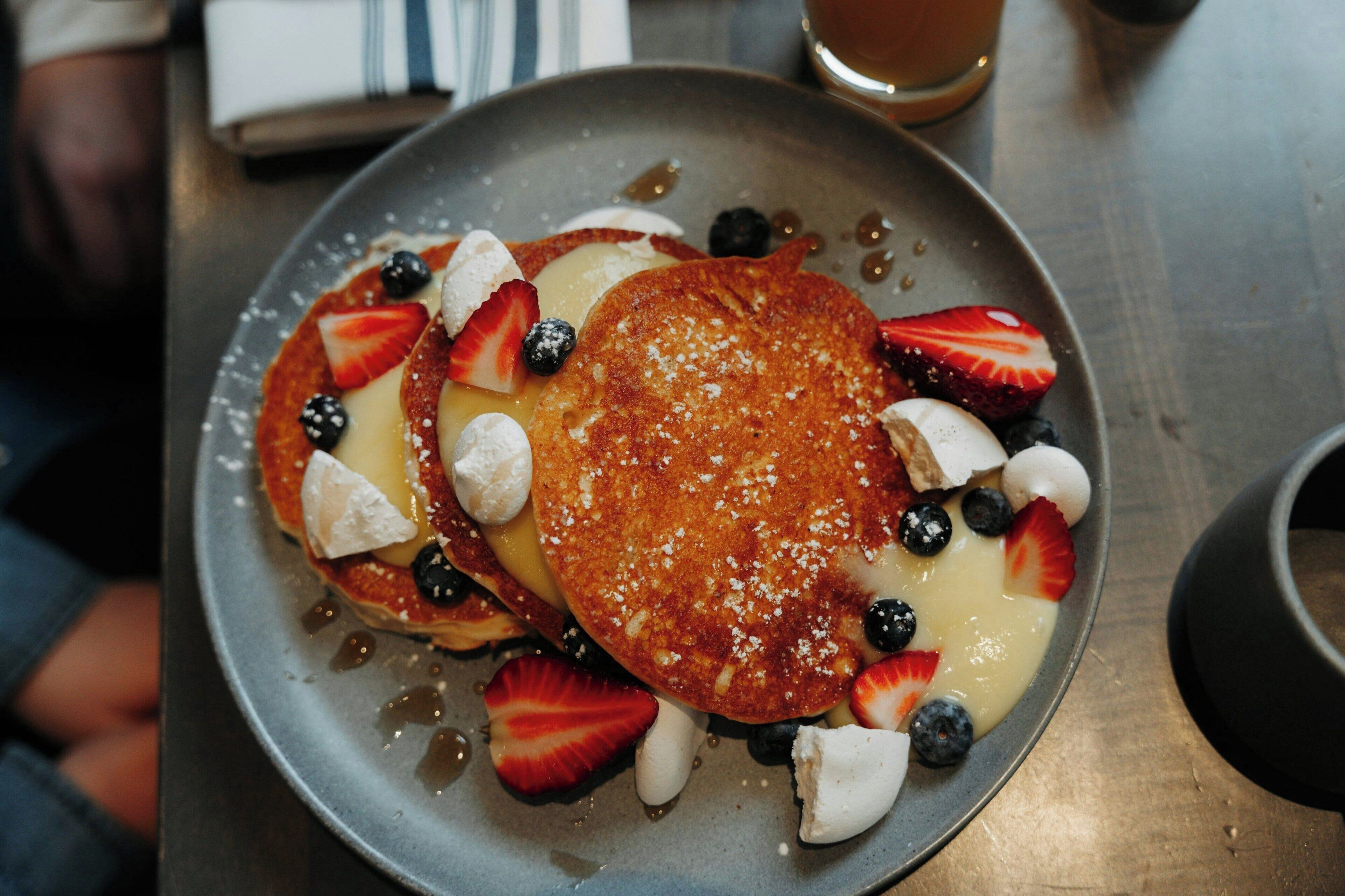 A plate of pancakes with strawberries, blueberries, and marshmallows.