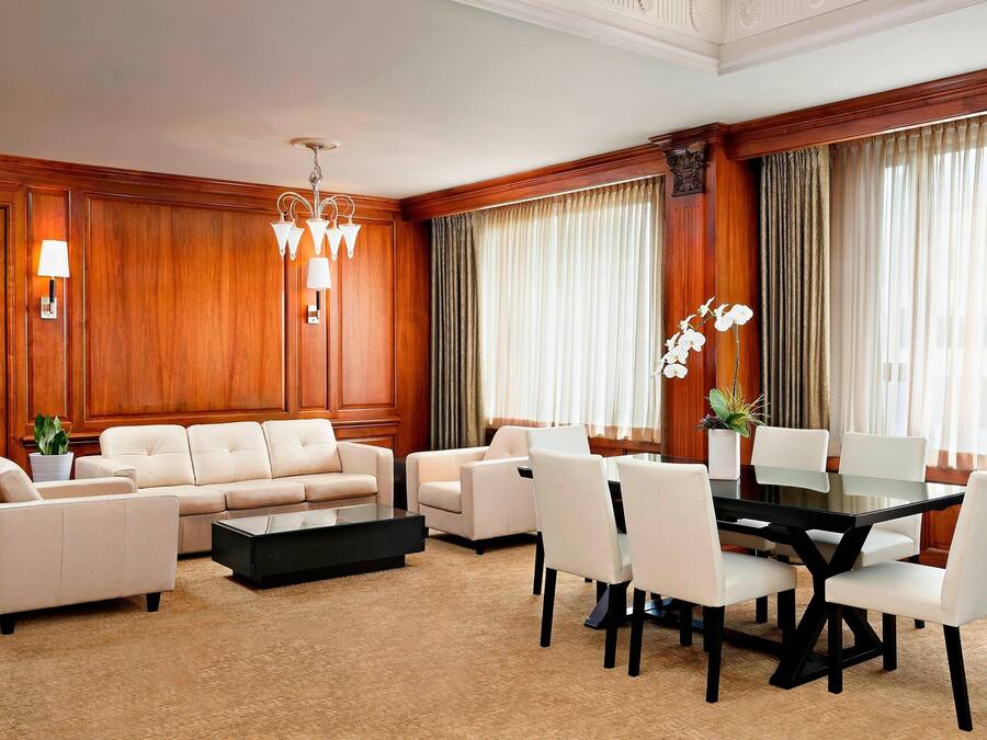A spacious room with a large sofa set, a dining table with chairs, and a coffee table.