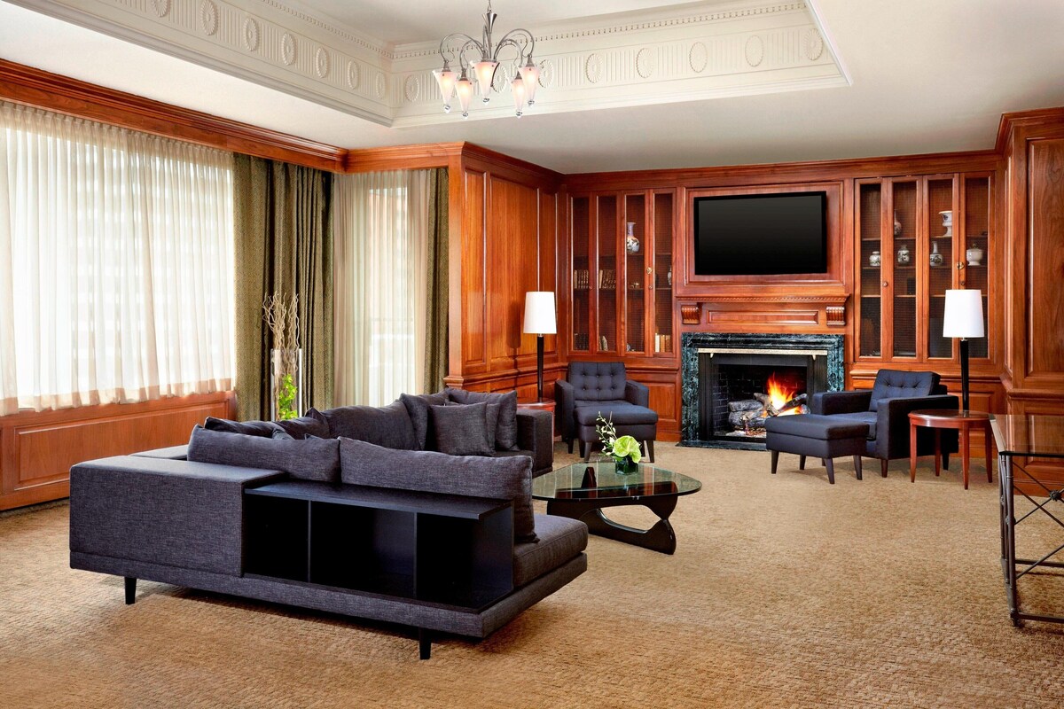 A spacious living room with a large sofa, armchairs, a fireplace, and a television.