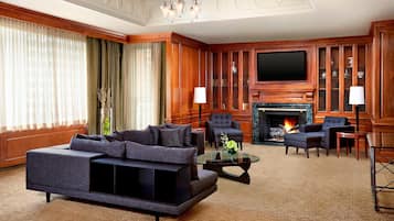 Un salón espacioso con un sofá grande, sillones, chimenea y televisor.