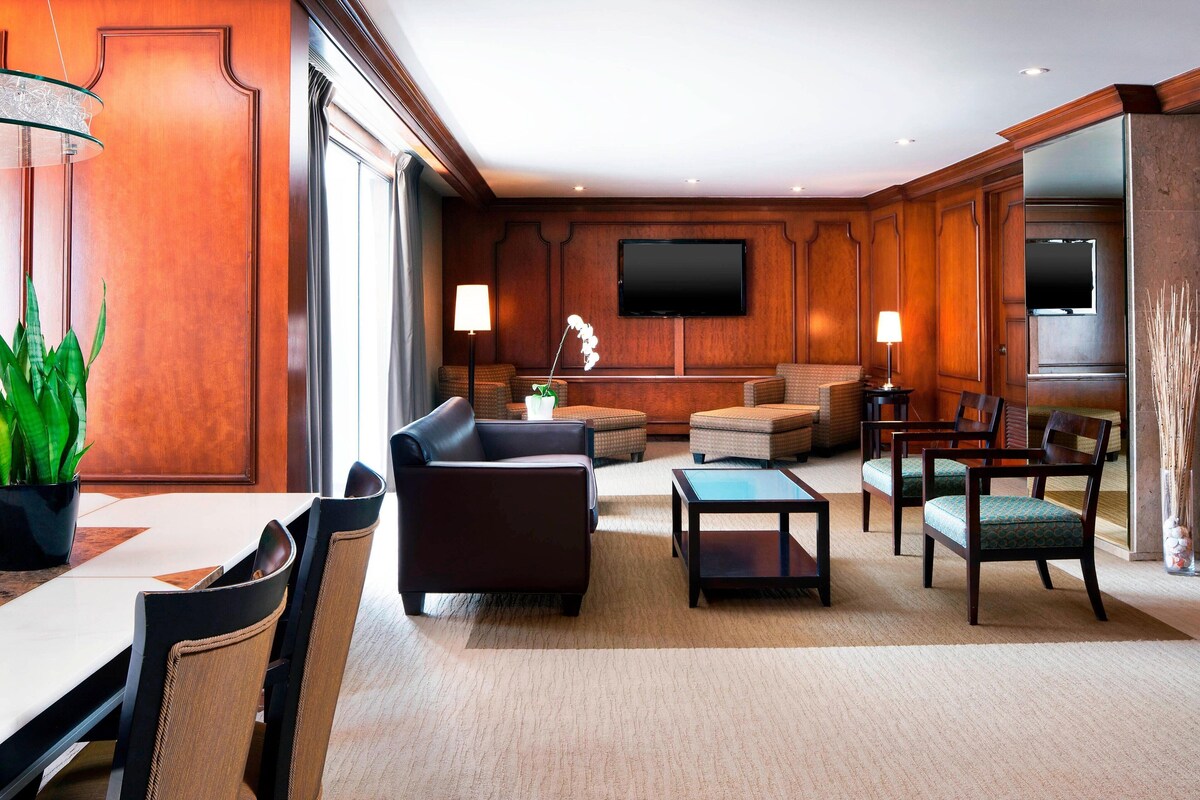 A spacious living room with a large flat-screen TV, comfortable seating, and a dining area with a table and chairs.