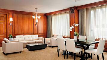 Habitación de hotel con sofá, una mesa de comedor con sillas, una mesita de centro y una planta en maceta.