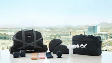 A Westin Hyperice massage device, a Westin branded massage bag, and a massage ball on a table with a city view in the background.