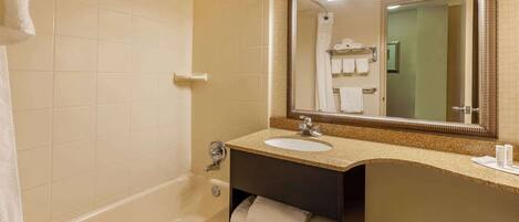 A bathroom with a bathtub, a sink, a vanity with a mirror, and a towel rack.