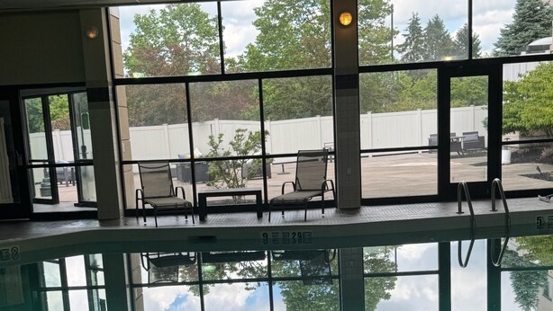 Une piscine intérieure avec des parois en verre transparent, offrant une vue sur l’extérieur, et un poste de surveillance pour le sauveteur.