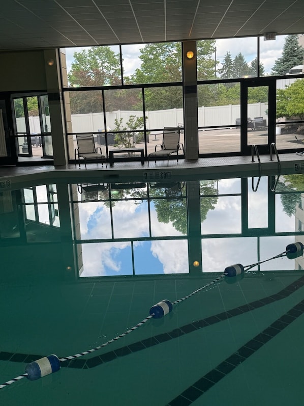 An indoor swimming pool with clear glass walls, a view of the outside, and a lifeguard chair.