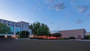 Un hôtel doté d’un bâtiment moderne, d’un parking et d’un espace paysager agrémenté d’arbres.