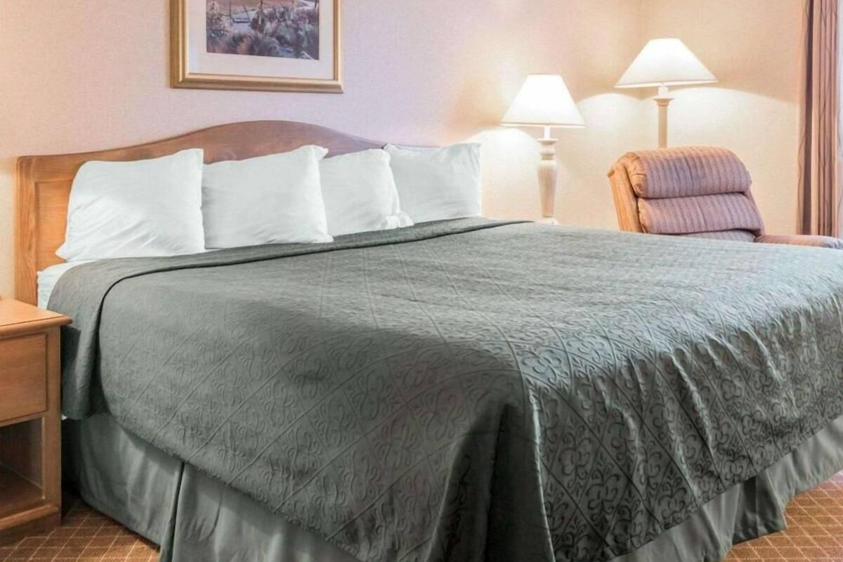 A hotel room with a bed, a nightstand, a chair, and a lamp.