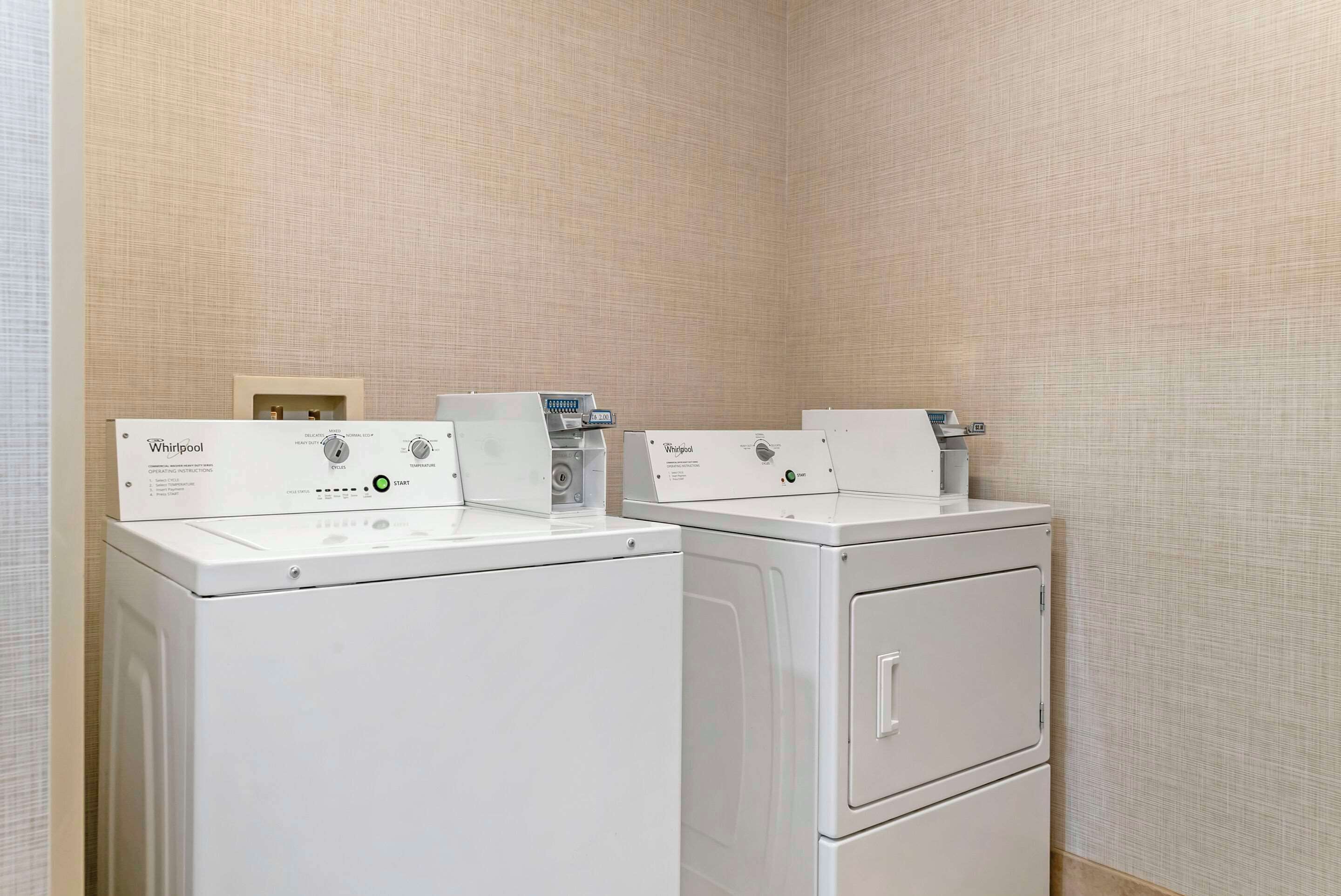 A laundry area with two Whirlpool washers and a stacked dryer.