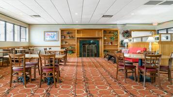 Un hall d’hôtel avec un tapis à motifs, des meubles en bois et une cheminée.