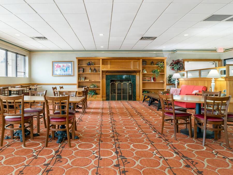 Un hall d’hôtel avec un tapis à motifs, des meubles en bois et une cheminée.