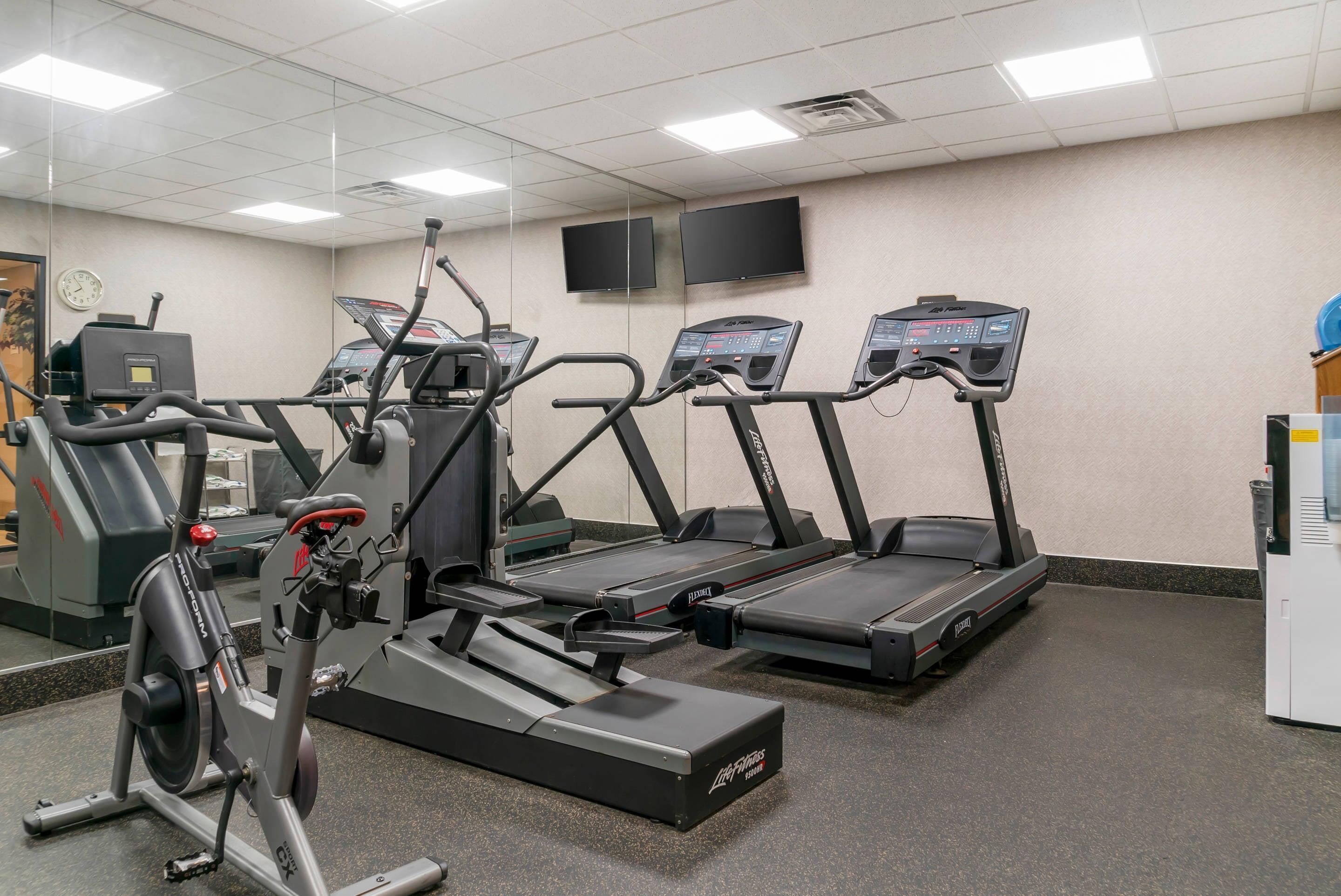 Un gimnasio con cintas de correr, elípticas y una bicicleta estática.