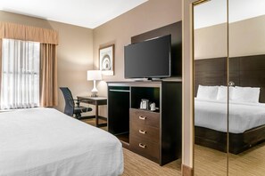 A hotel room with a large bed, a desk with a chair, a television, and a wardrobe. - Quality Inn & Suites Monroe (Monroe)