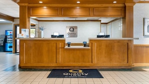 Una taquilla amb un cartell que diu "Quality by Choice Hotels", un quiosc digital i una zona de recepció amb un paviment de rajola.