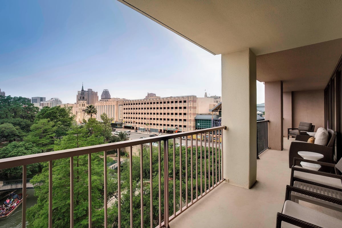 Un balcon offrant une vue sur le paysage urbain, avec notamment un grand immeuble et des espaces verts.