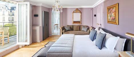 Un dormitorio espacioso con una cama grande, una zona de estar y un balcón con vistas a edificios.